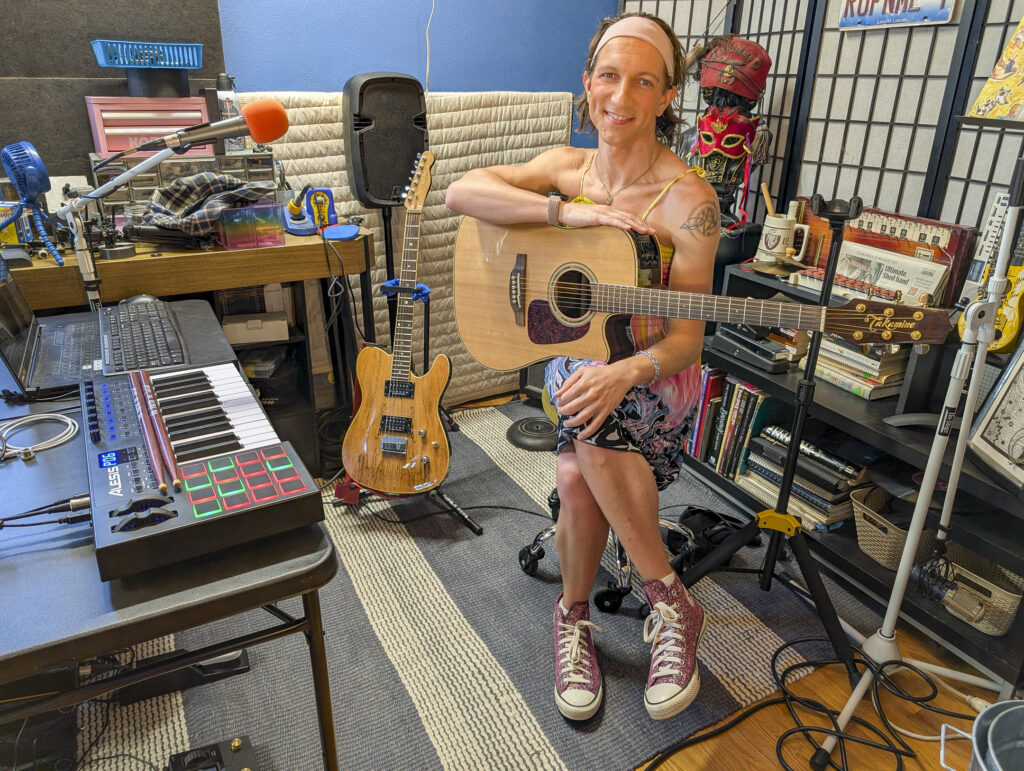 Aletha Flo posing in her studio with a guitar