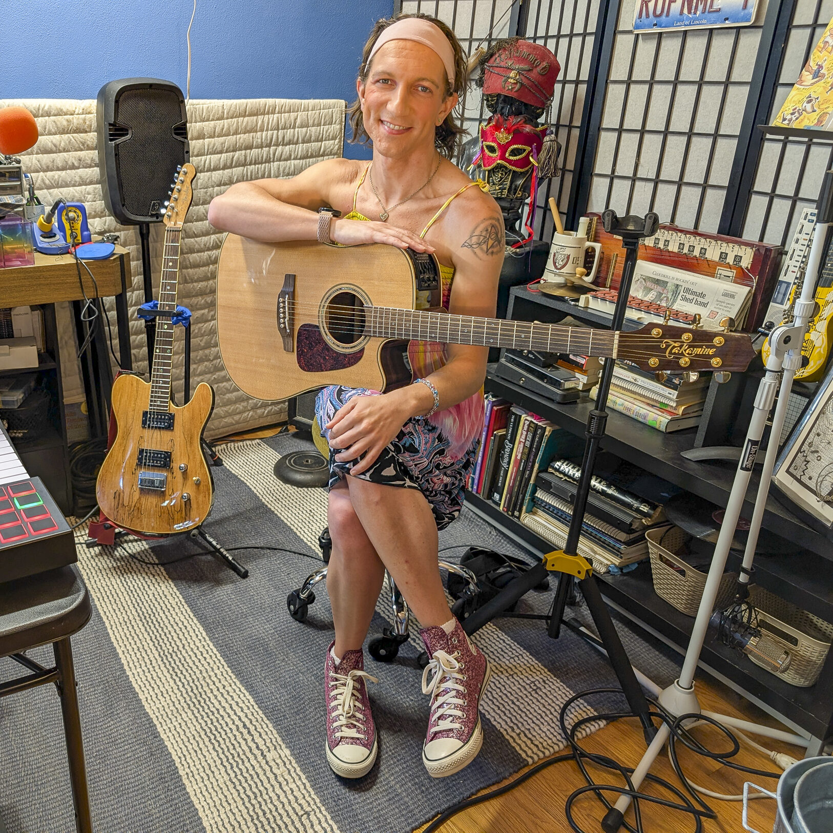 Aletha Flo posing in her studio with a guitar